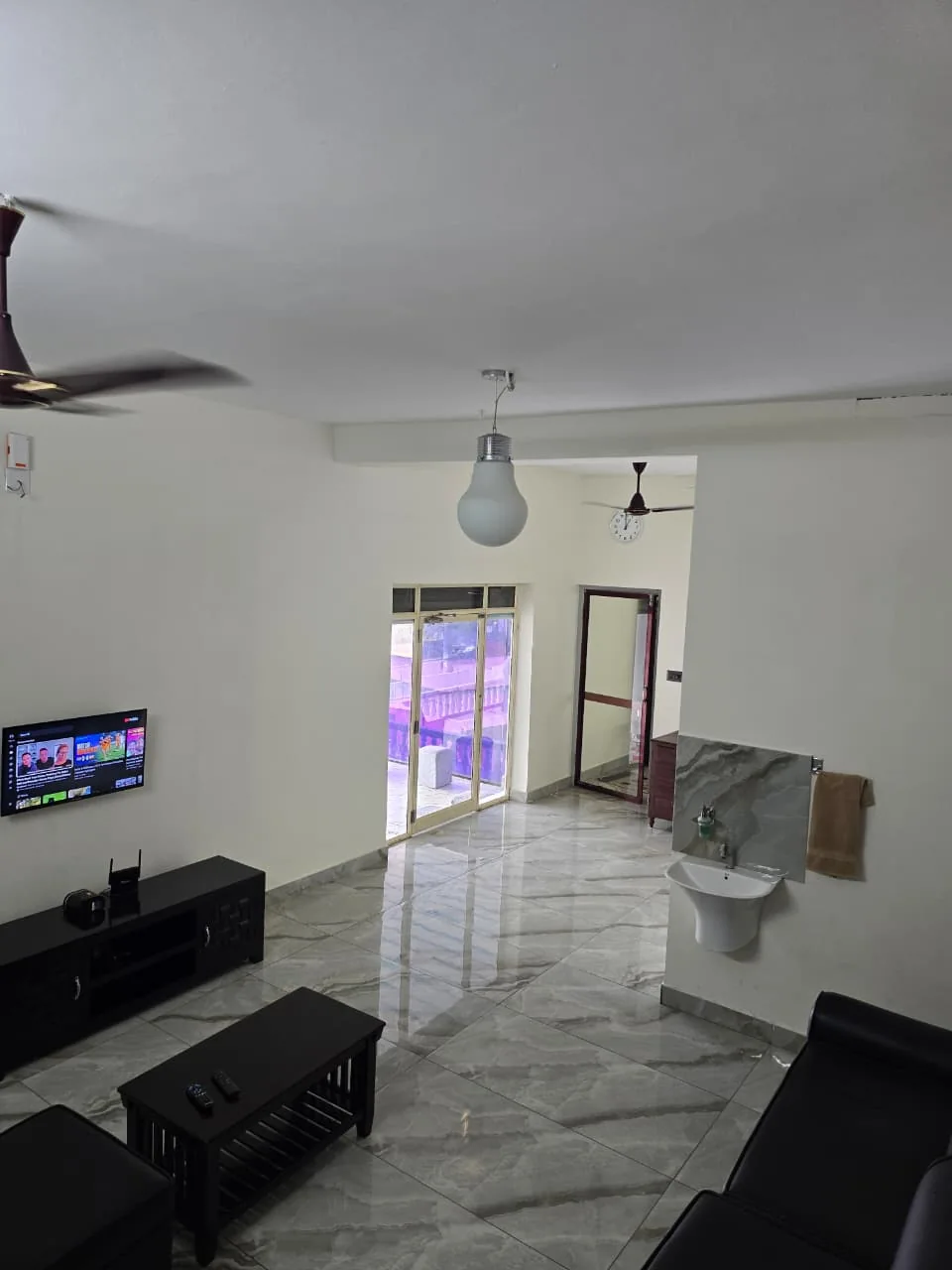 Spacious Grey Oasis living hall with sofas, television and marble-look floor
