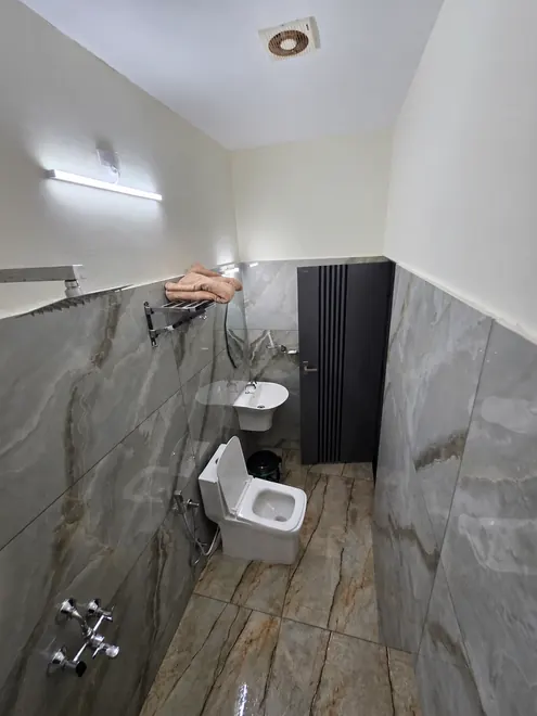 Bathroom with marble-look wall and floor tiles, at Grey Oasis Homestay in Thrissur