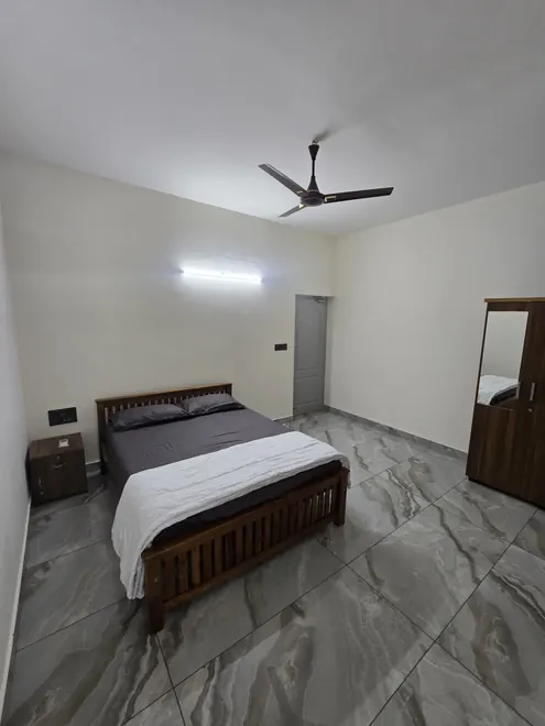 Guest bedroom with wooden bed and tiled flooring at Grey Oasis in Thrissur